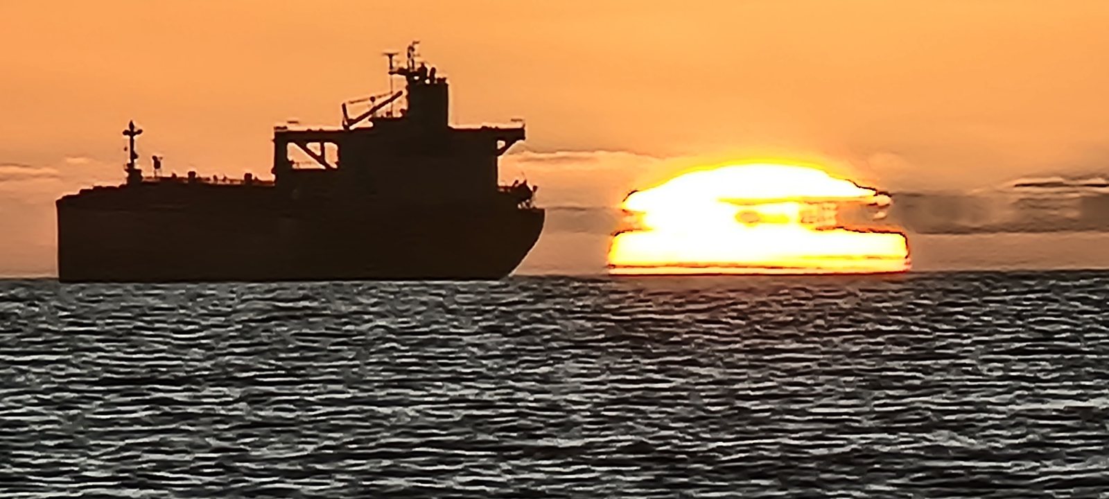 A ship silhouetted against the setting sun over Table Bay