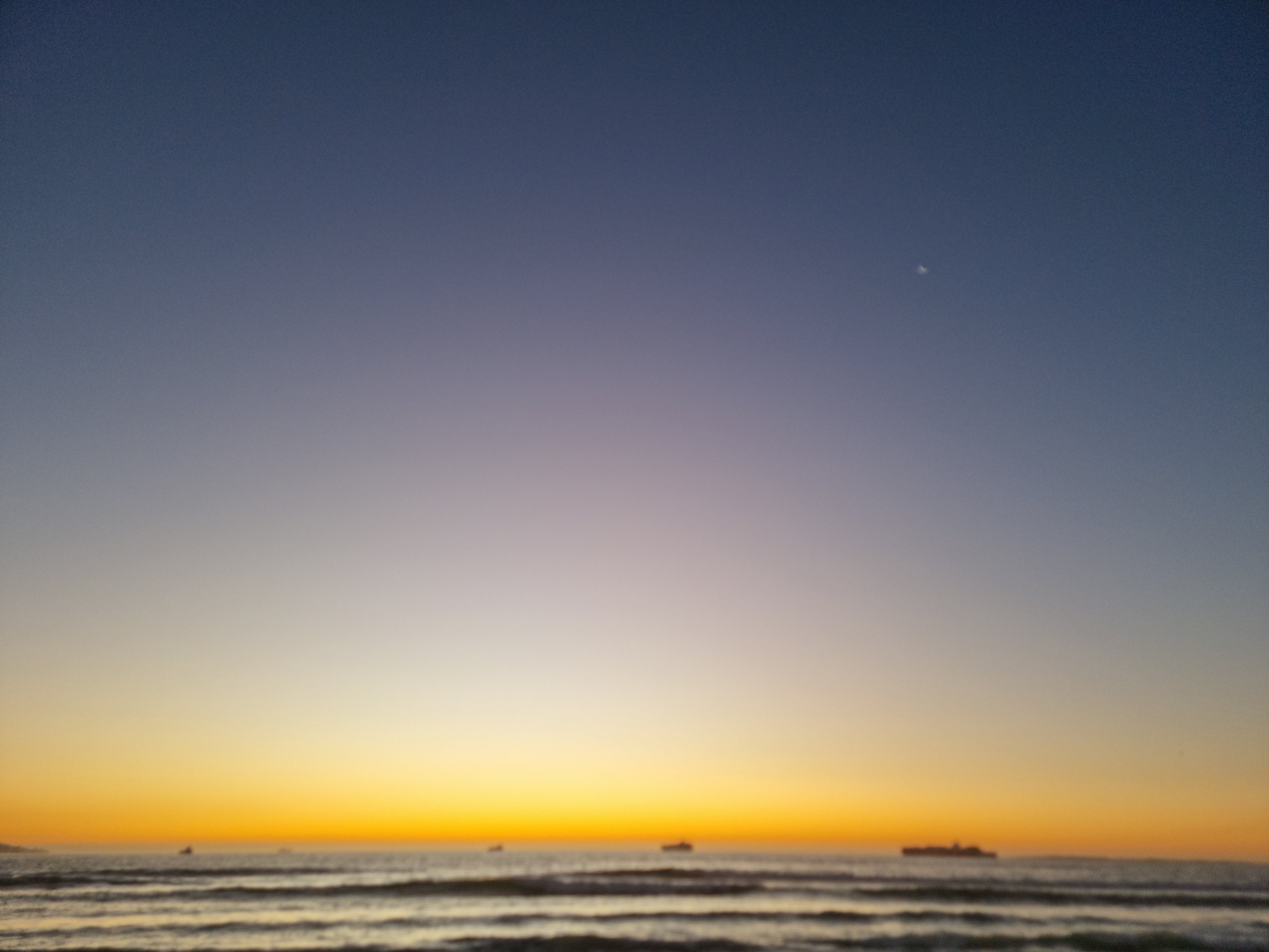 Wide panorama of the sky and sea at Bloubergstrand after sunset with ships on the horizon