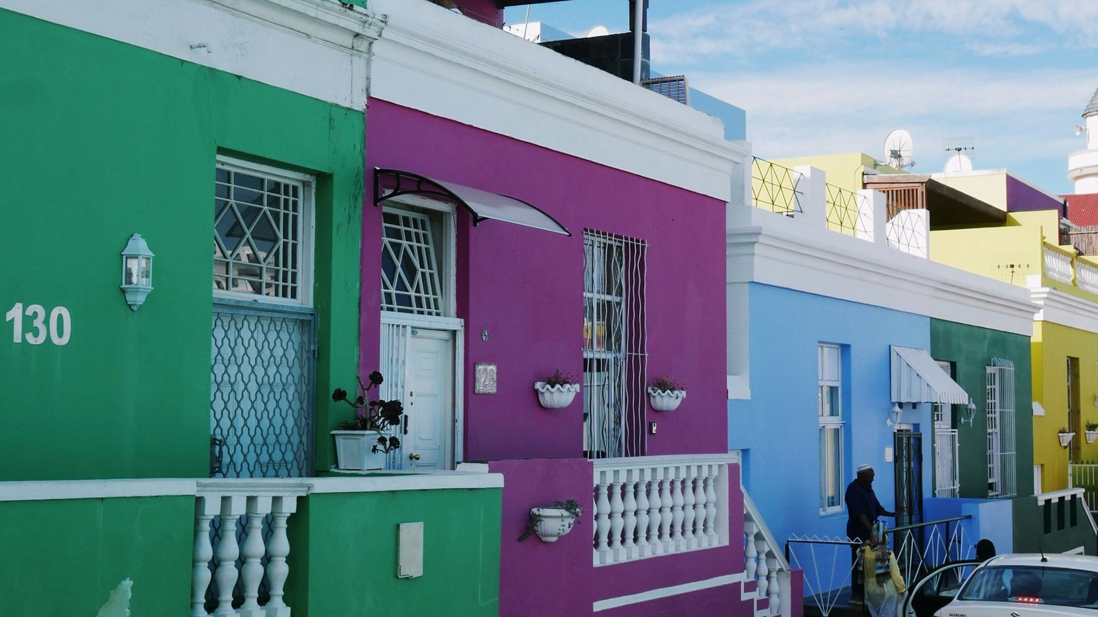 The brightly painted green, purple, blue and yellow houses of the Bo-Kaap on a cobbled street in Cape Town