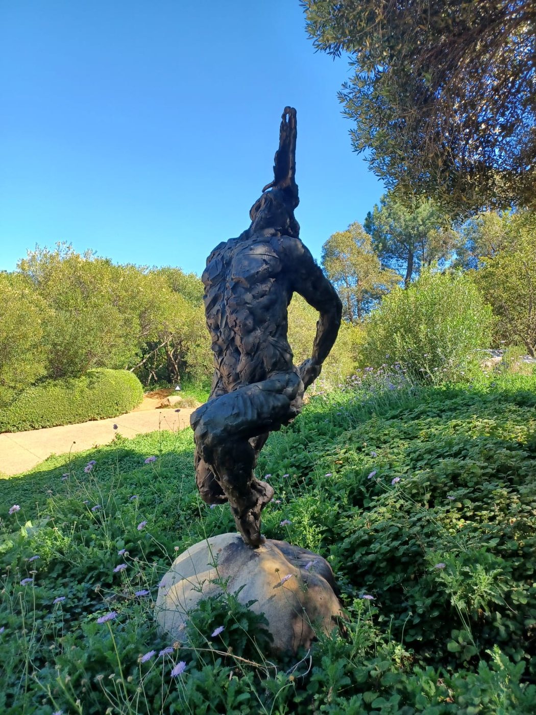 Standing bronze trans-figure balanced on a boulder by Dylan Lewis