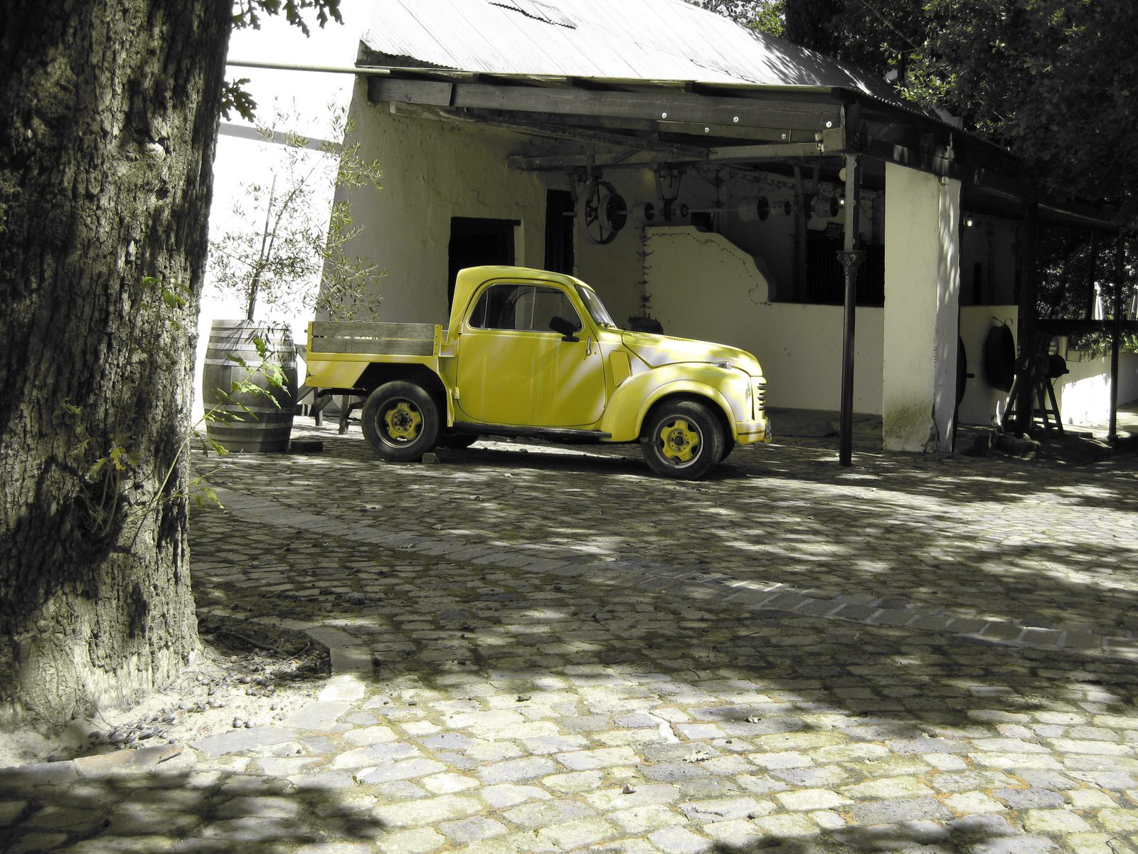 Vintage yellow pickup truck parked on cobbles at Muratie wine estate