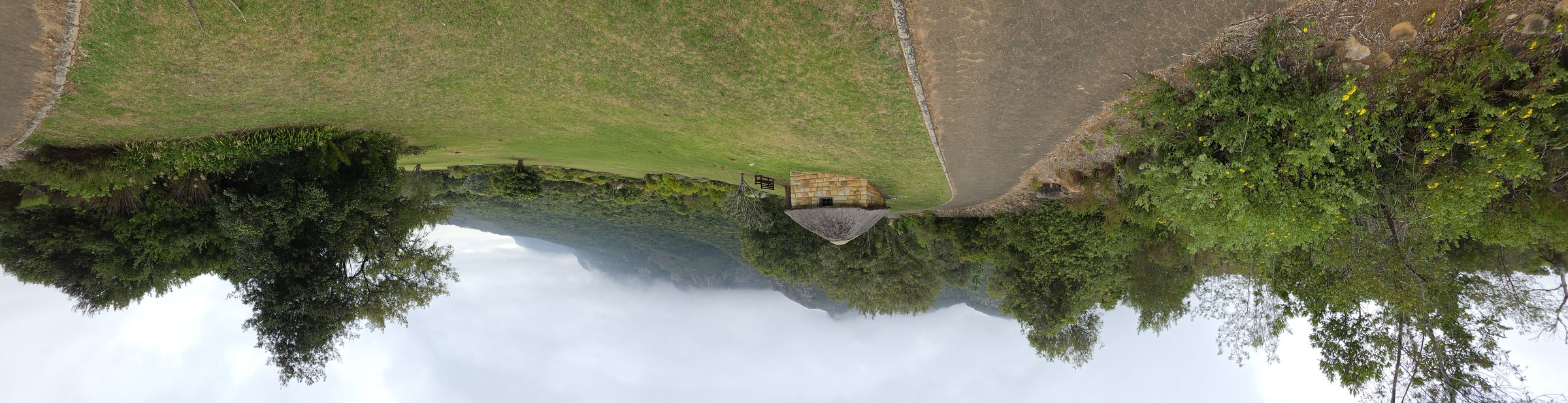 Panorama of Kirstenbosch gardens with thatched stone shelter and mist over the mountains