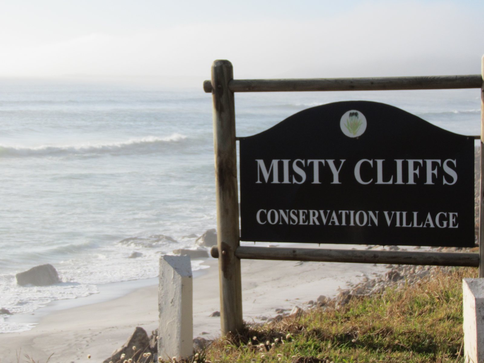 The Misty Cliffs Conservation Village sign with the misty Atlantic behind