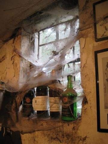 Cobwebbed windowsill with old wine bottles inside the historic Muratie cellar
