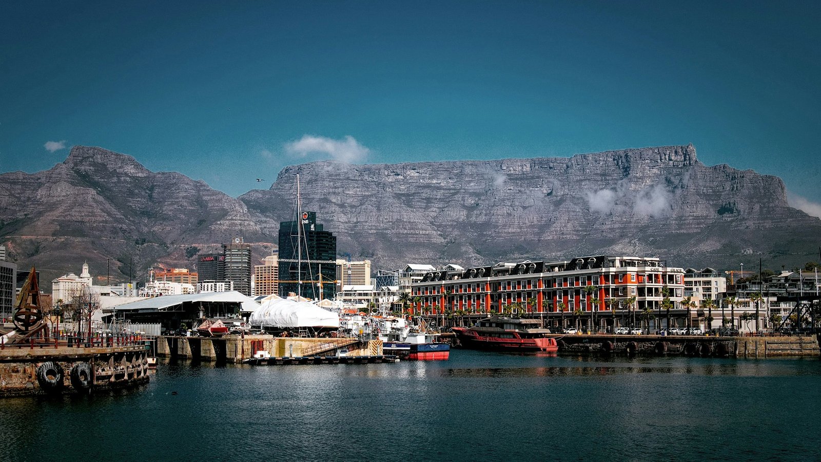 The V&A Waterfront harbour with boats and historic buildings beneath Table Mountain, Cape Town